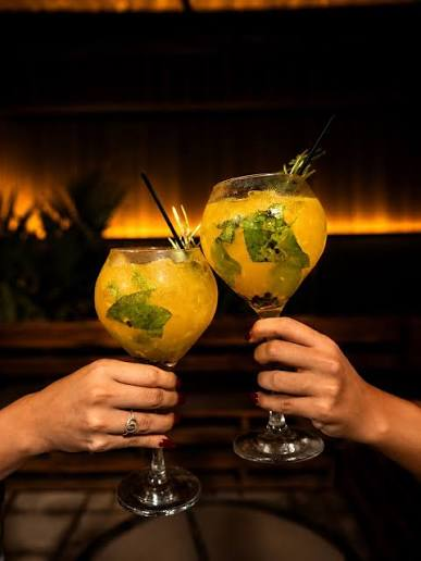 Brinde com dois drinks de frutas amarelos decorados com hortelã